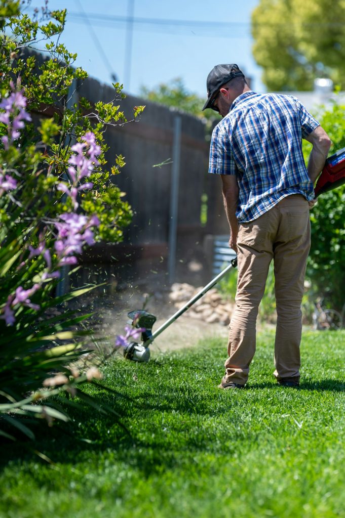 Gardener edging a lawn with a string trimmer